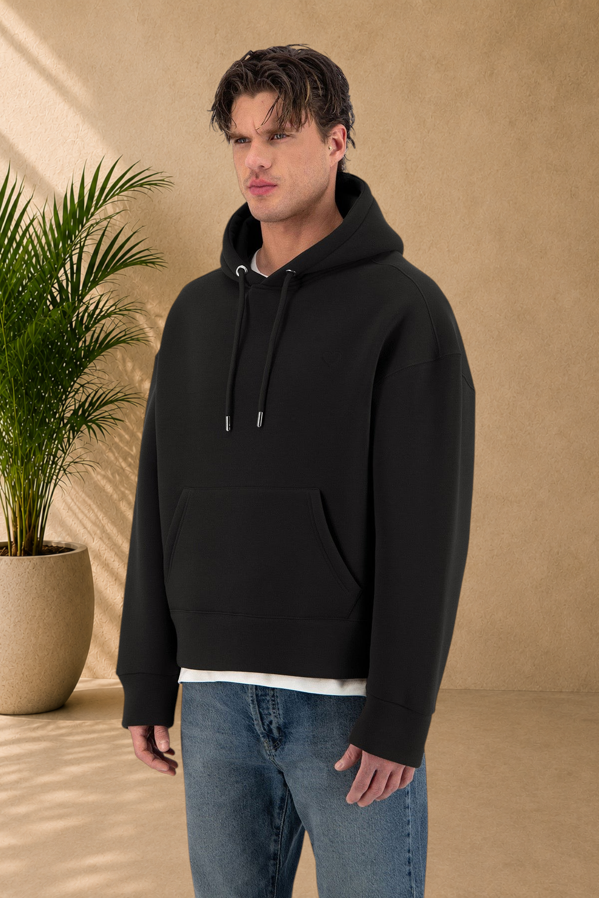 Stayin black quilted hoodie with a small heart detail worn by a male model in a studio setting