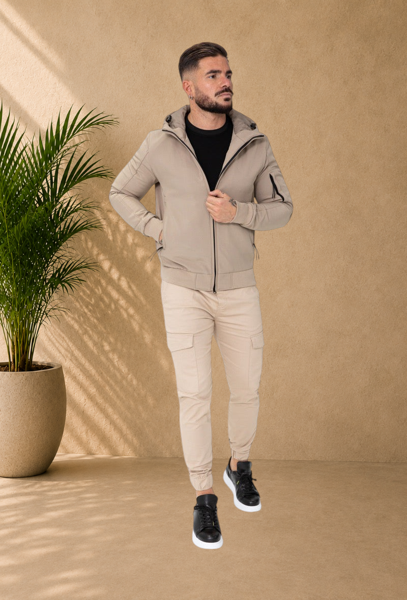 Stayin beige hooded windbreaker jacket worn by a male model with matching cargo joggers and black sneakers