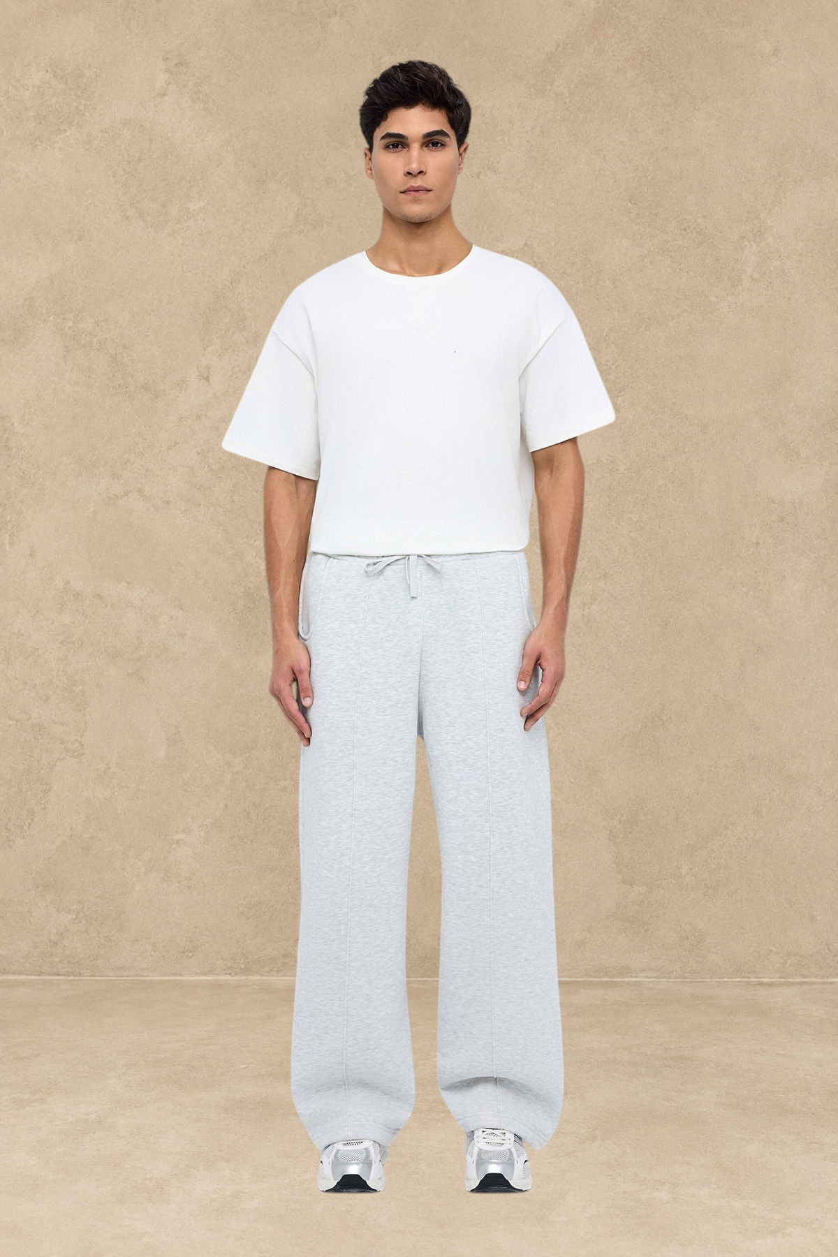 Homme portant un pantalon jogging large gris Stayin avec un t-shirt blanc et des baskets sur fond blanc