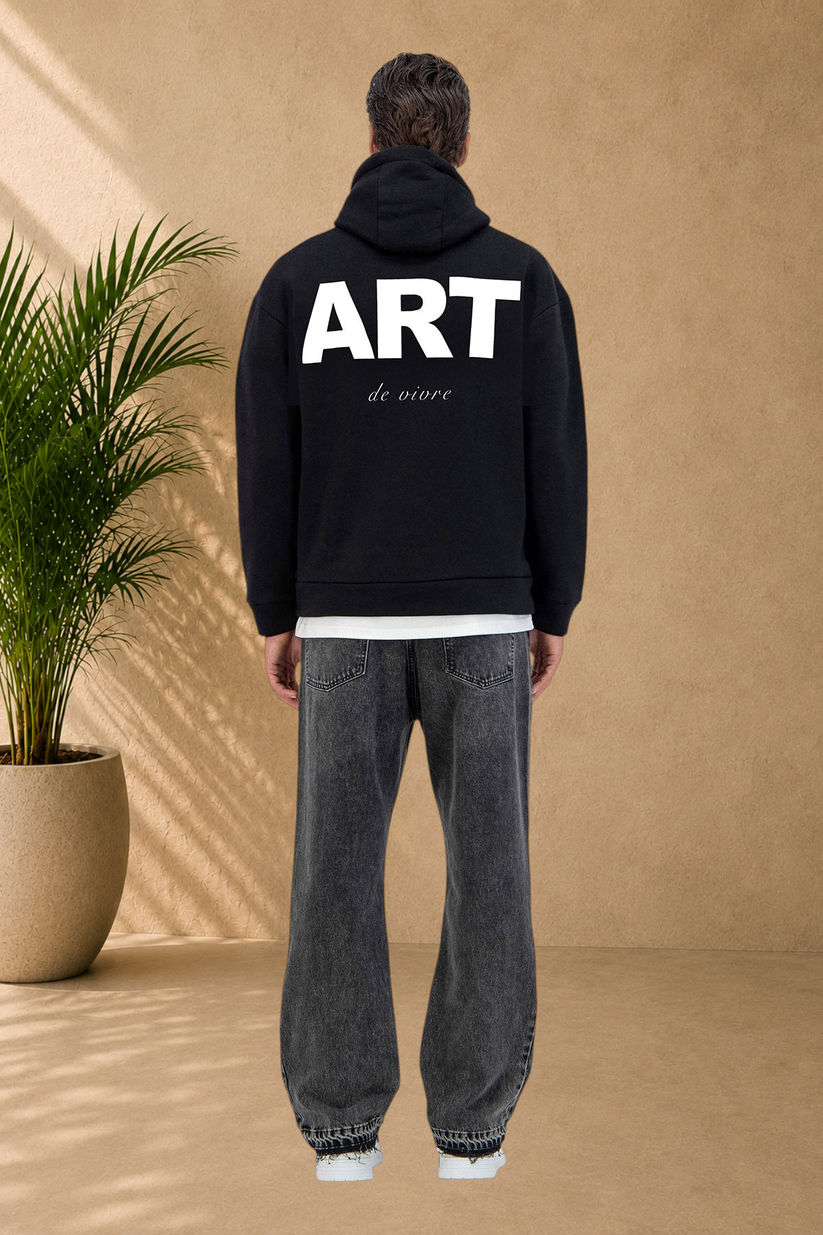 Stayin black quilted hoodie with ART graphic on back worn by a model in grey jeans