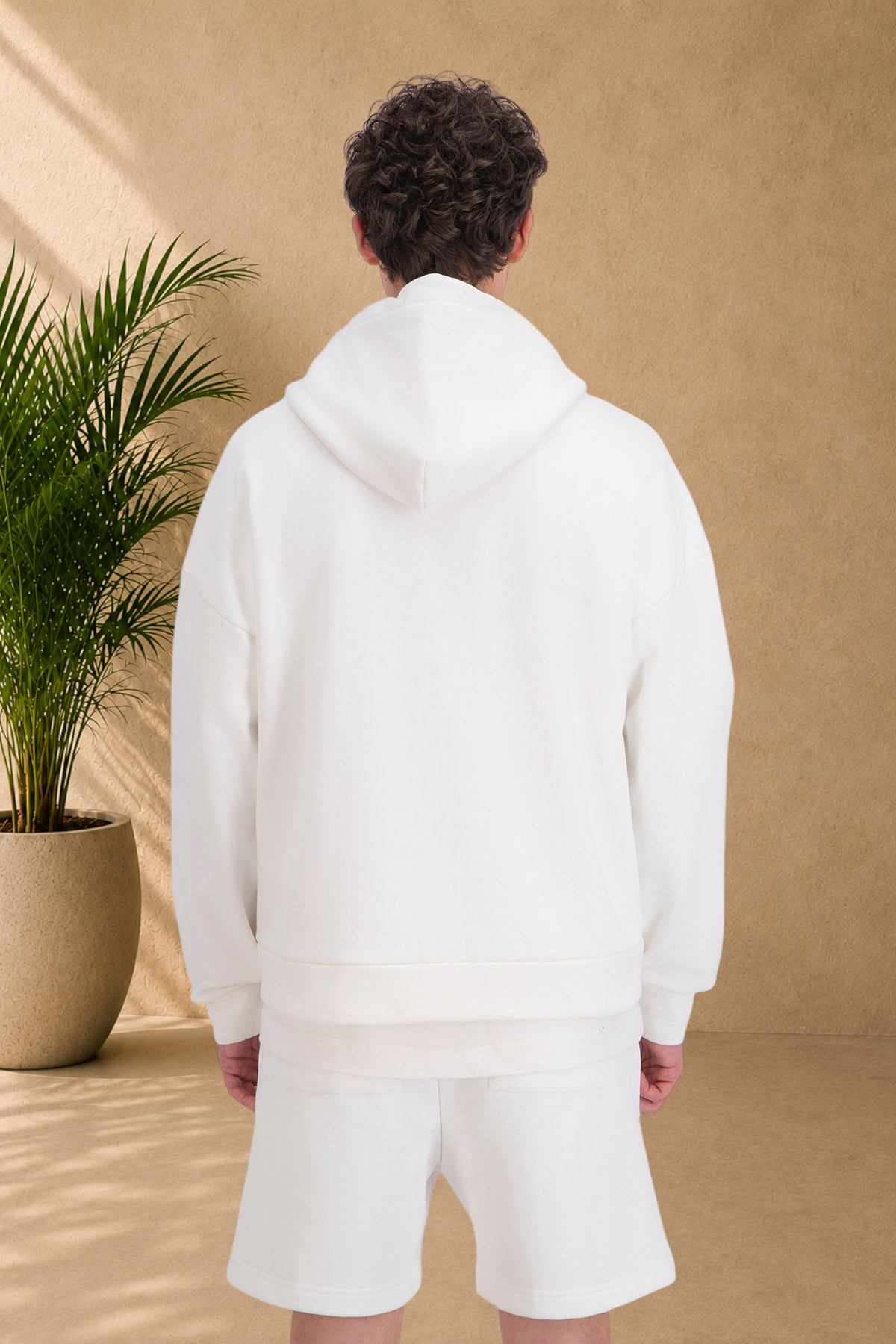 Stayin white quilted zip-up hoodie with hood, worn by a model against a neutral background with a potted plant.