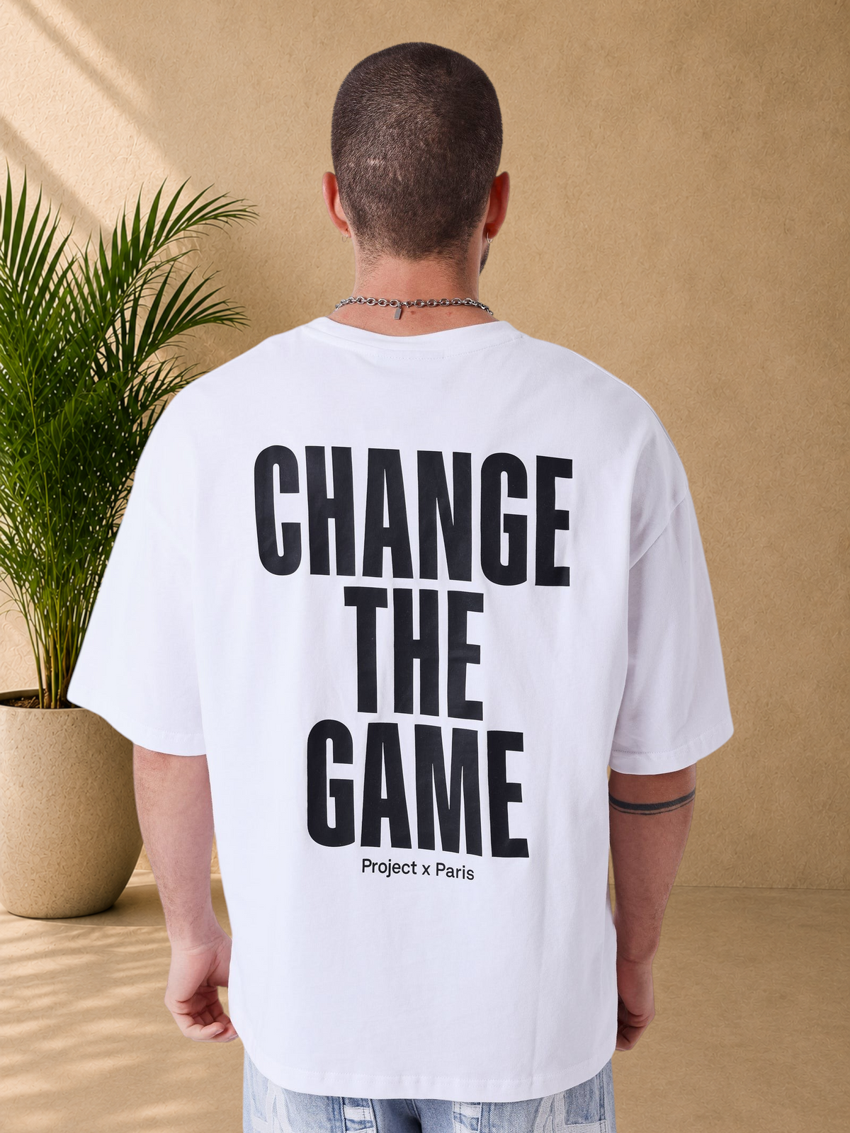 Stayin white boxy fit cotton t-shirt with black Change the Game slogan print on the back, worn by a man