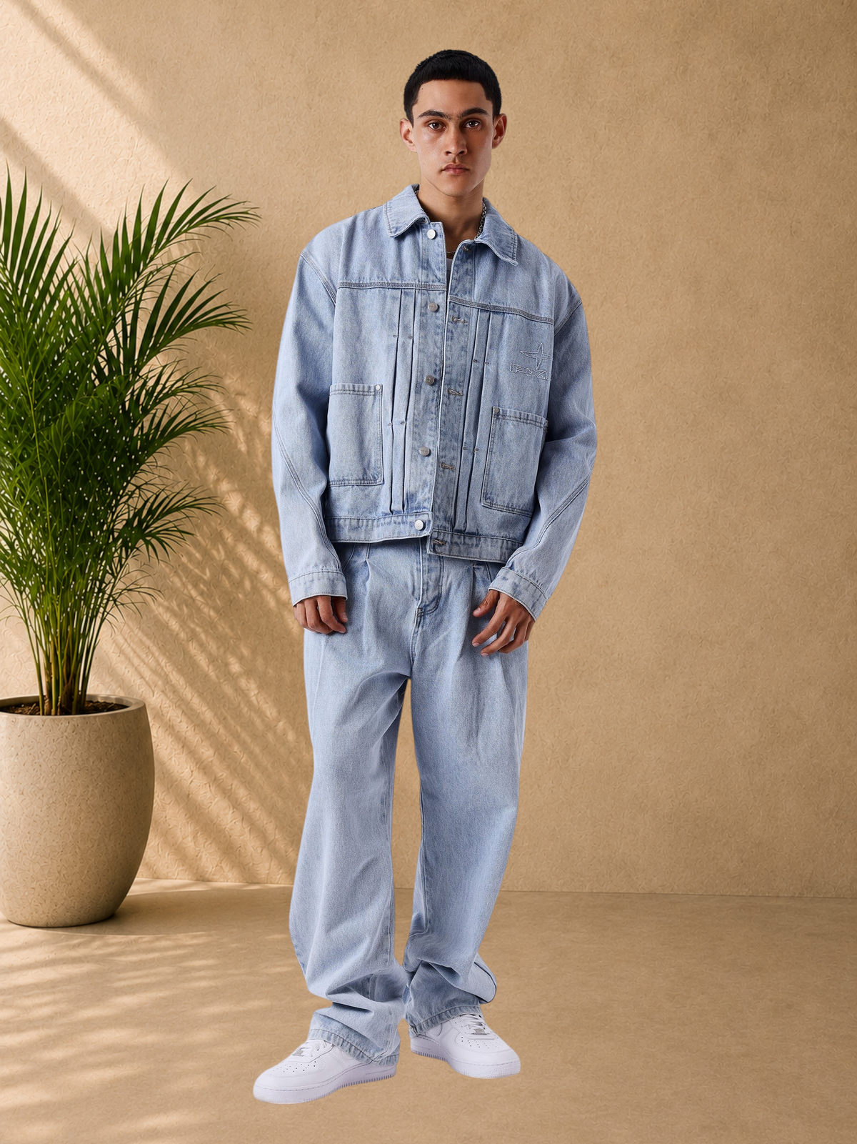 Stayin model wearing a light blue loose-fit denim jacket and matching jeans with front pleats and button closure