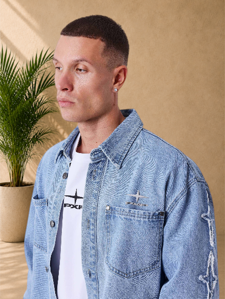 Stayin PXP Polaris blue denim jacket with loose fit, chest pockets, and metallic logo detail on a male model