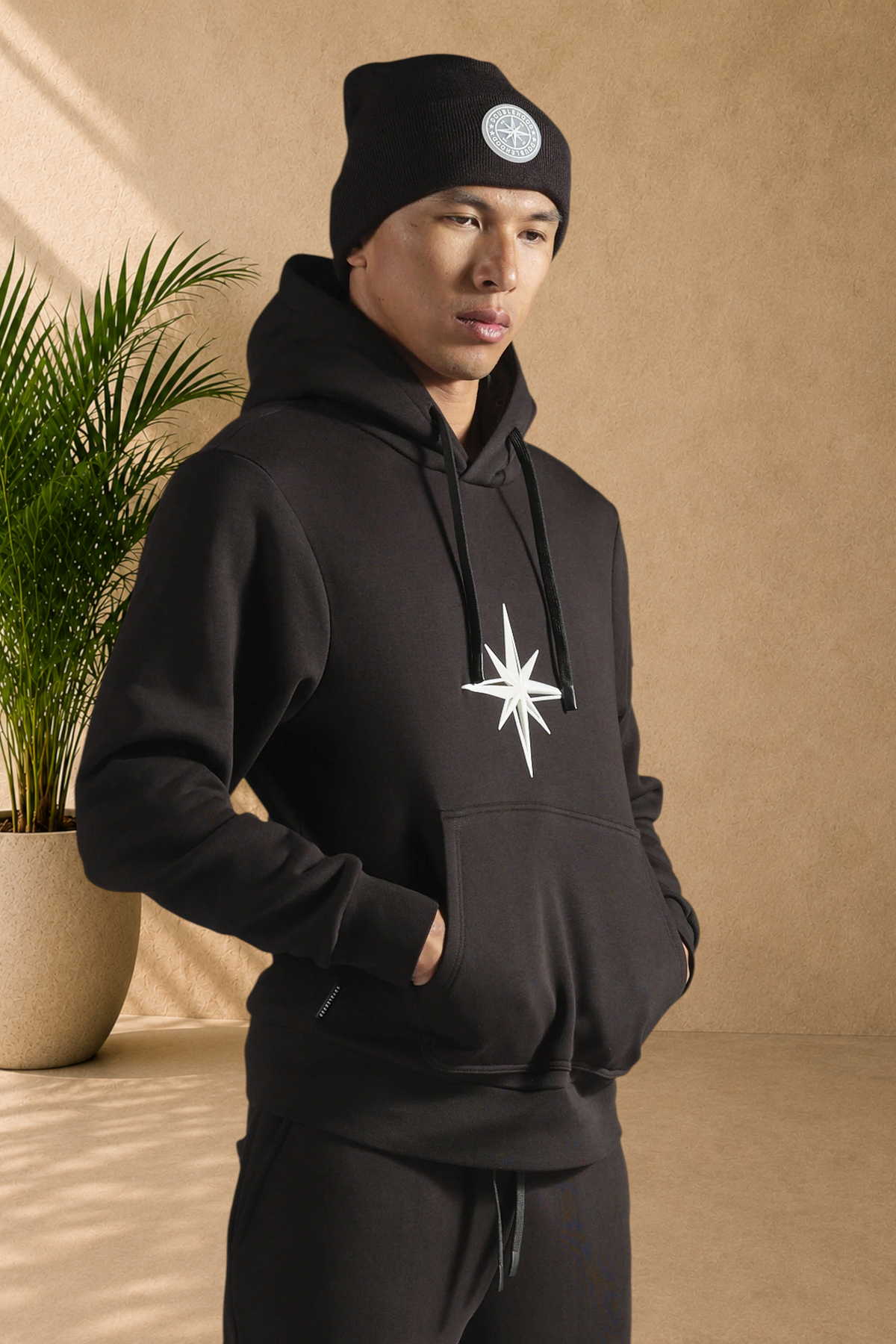 Stayin black doublehood sweatshirt with a white star graphic, worn by a man in a matching beanie.