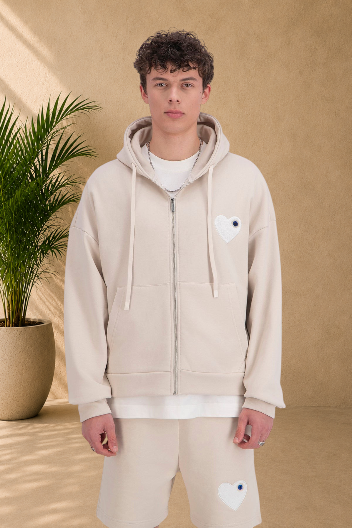 Stayin beige quilted zip-up hoodie with a white heart patch worn by a male model