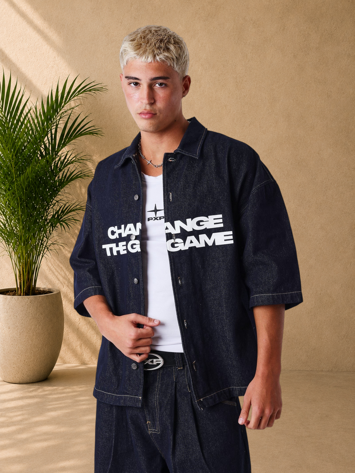 Stayin oversized dark denim short sleeve shirt with white Change The Game graphic print worn by a male model