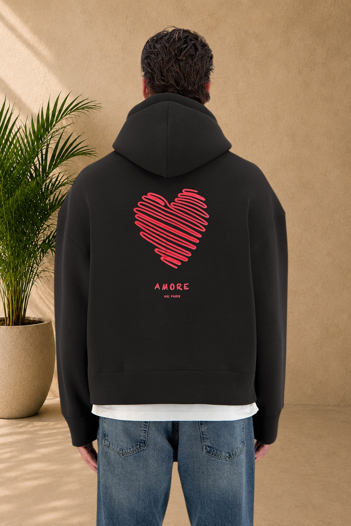 Stayin black hoodie with a red scribbled heart graphic and Amore text on the back, worn by a model.