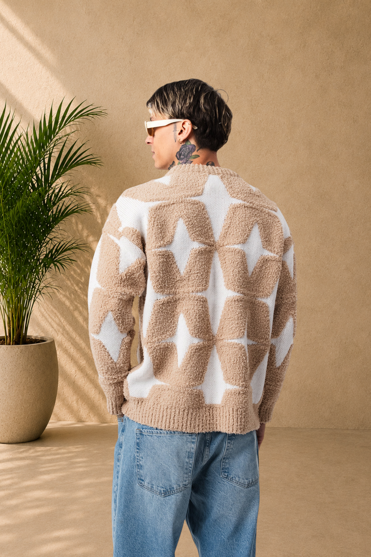 Stayin fluffy beige and white star pattern sweater worn by a man with sunglasses, back view