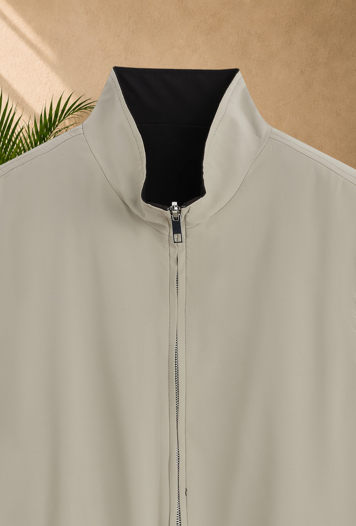 Stayin reversible sleeveless zip-up vest in beige and black with a high collar and smooth finish