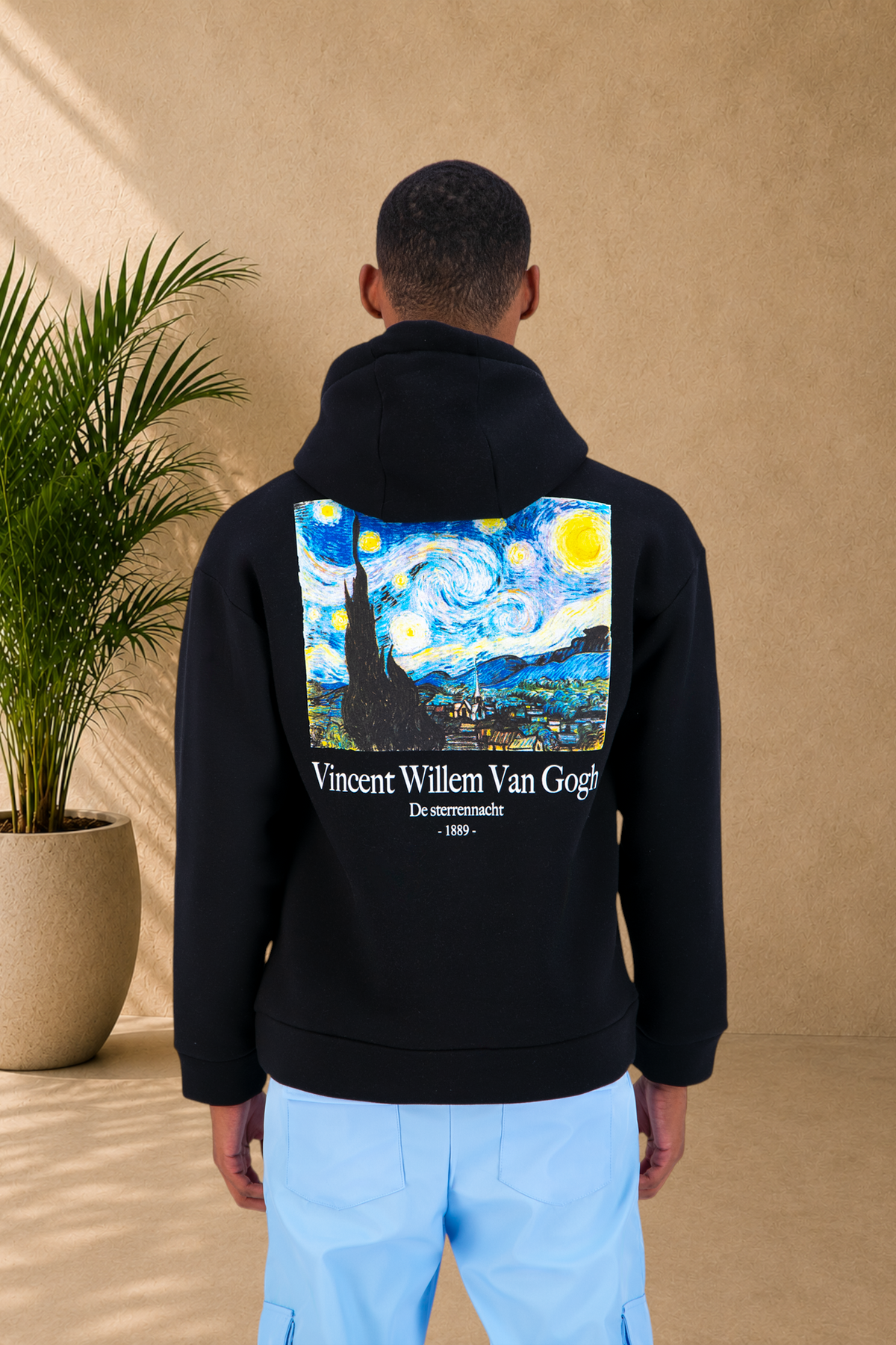Stayin black hoodie featuring a large Starry Night print by Van Gogh on the back, worn by a model in a studio.