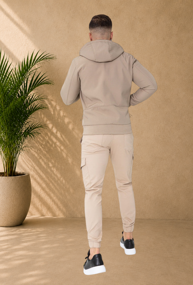 Stayin beige hooded windbreaker jacket worn by a man from the back view, paired with matching cargo joggers.