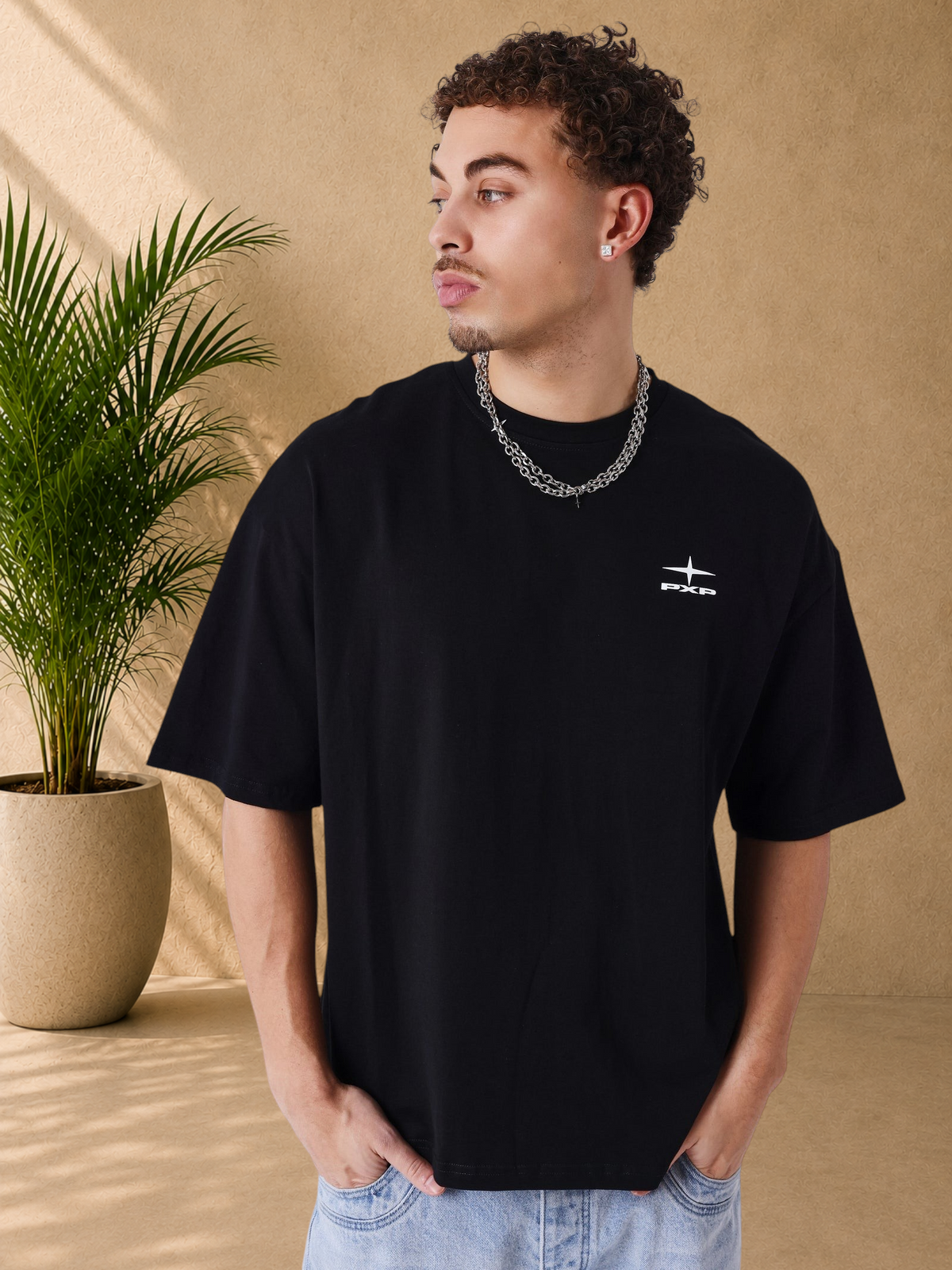 Stayin PXP black boxy fit cotton t-shirt with white logo on chest, worn by a man with a silver chain necklace.
