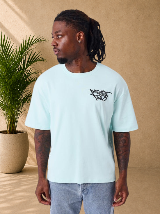 Stayin PXP oversized light green cotton t-shirt with black graffiti logo on chest, worn by a man.