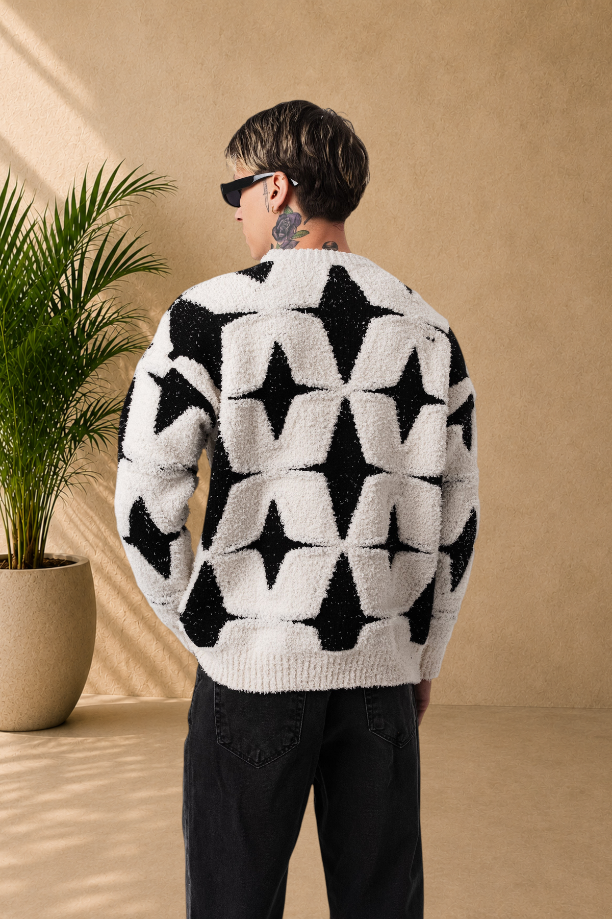 Stayin fluffy sweater in white and black with a star pattern, worn by a model from the back view.