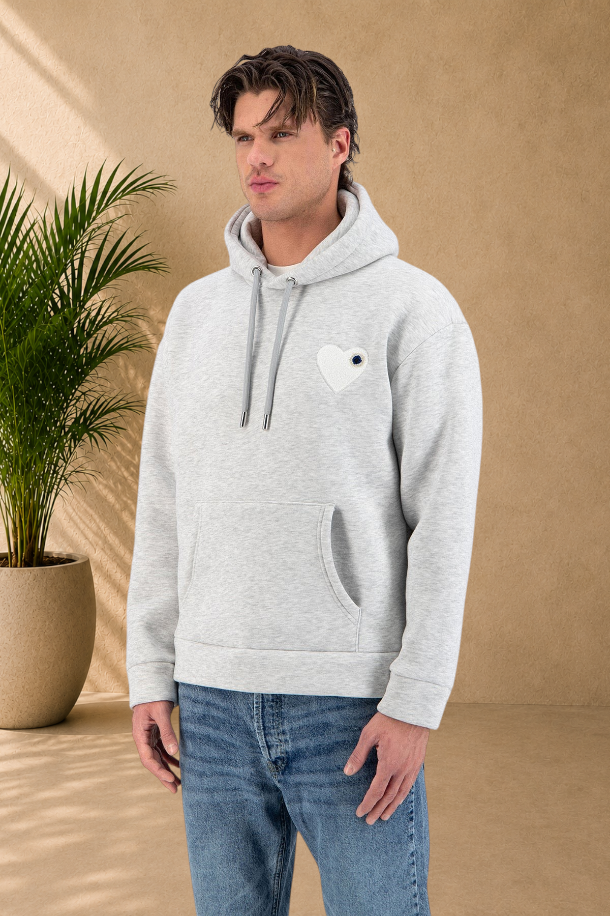 Stayin grey quilted hoodie with a black heart patch worn by a male model on a white background