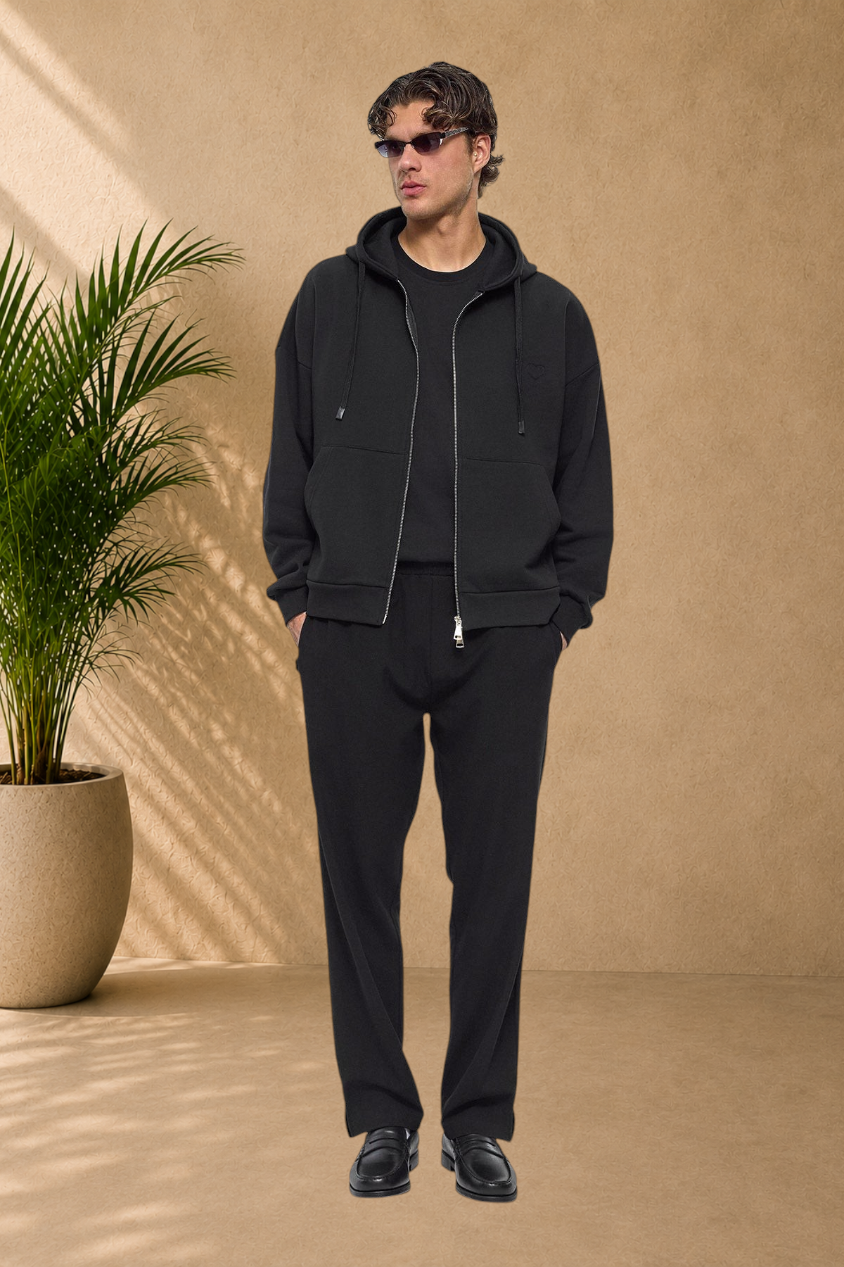 Stayin black quilted zip-up hoodie with heart detail worn by a male model in a full-body studio shot.