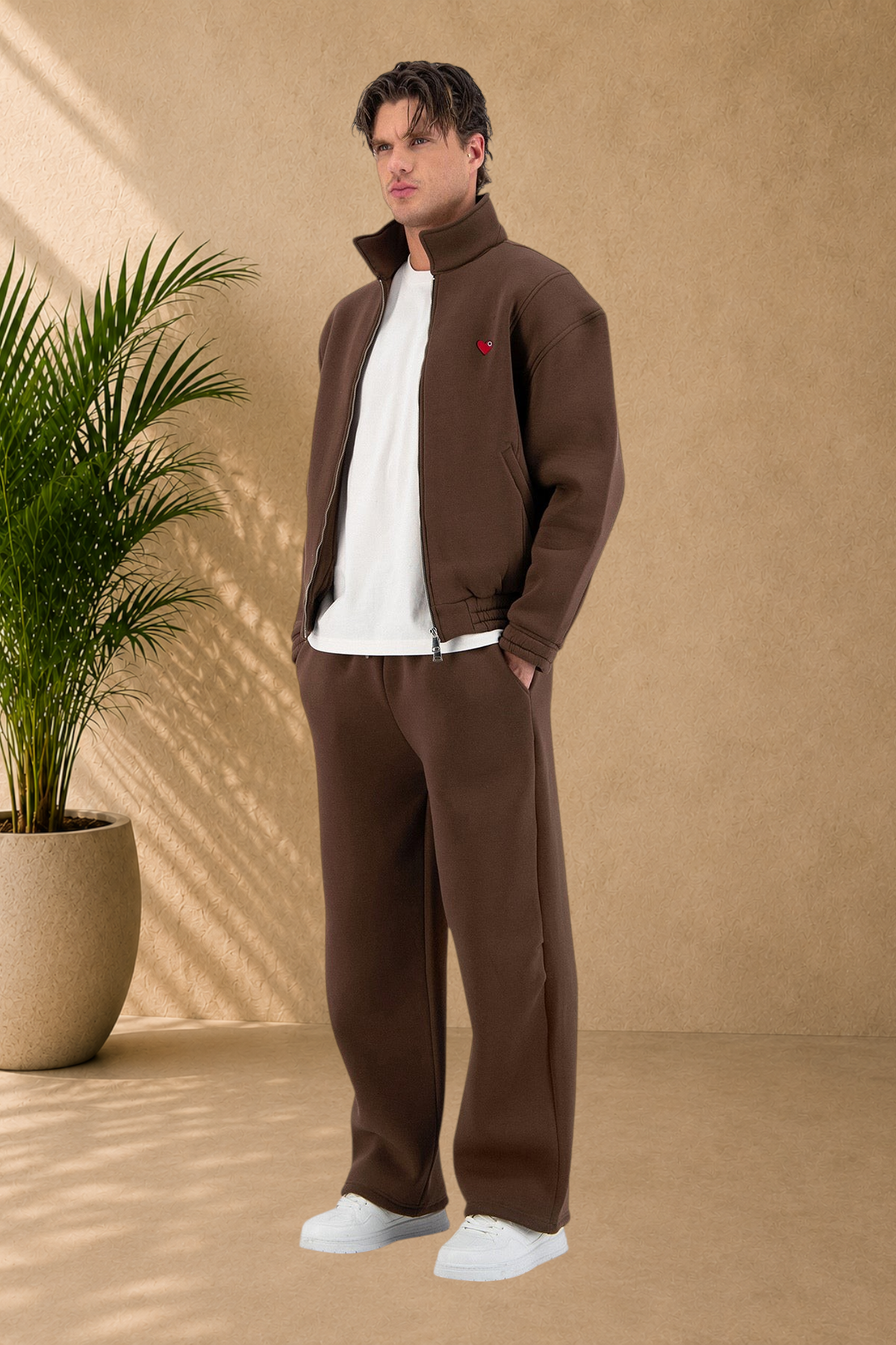 Stayin brown oversized zip-up jacket with a small red heart detail worn by a model in a studio setting