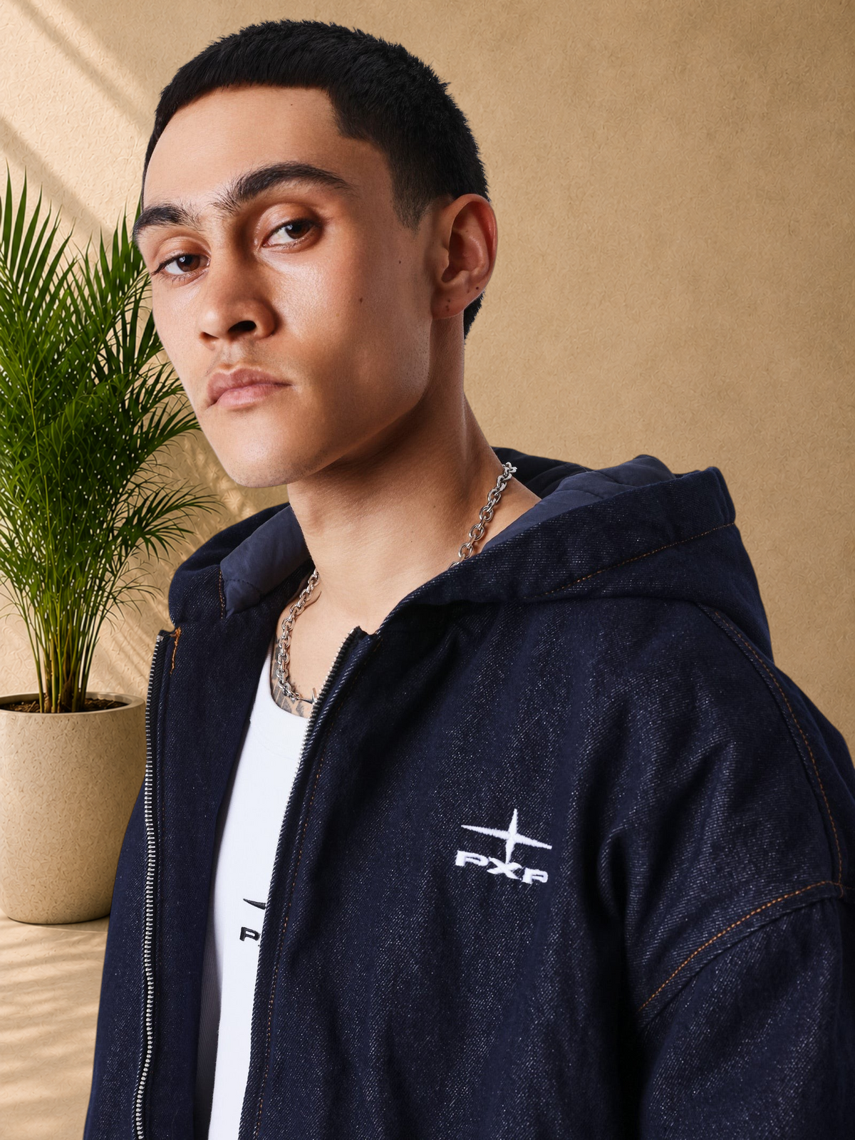 Stayin model wearing a dark blue denim zip-up hoodie by PXP with a boxy fit and embroidered chest logo