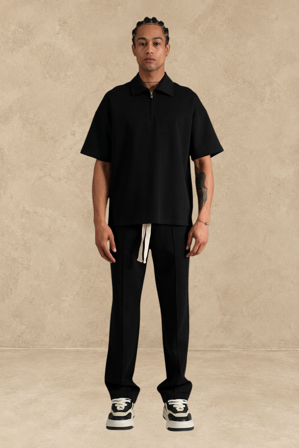 Mannequin portant un ensemble Stayin noir composé d'un polo à zip et d'un pantalon large en polyester