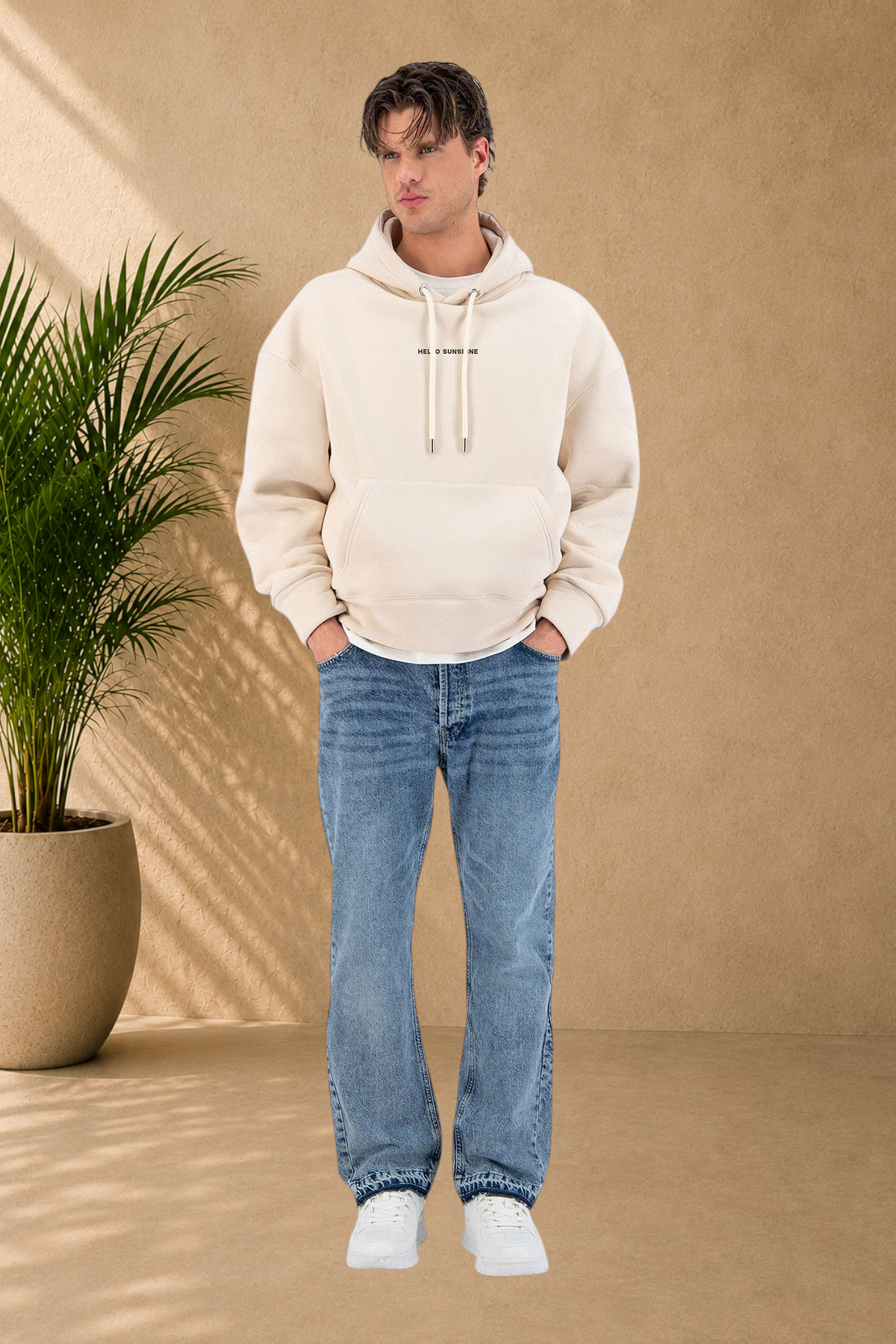 Stayin beige quilted hoodie with Hello Sunshine print worn by a male model with blue jeans and white sneakers