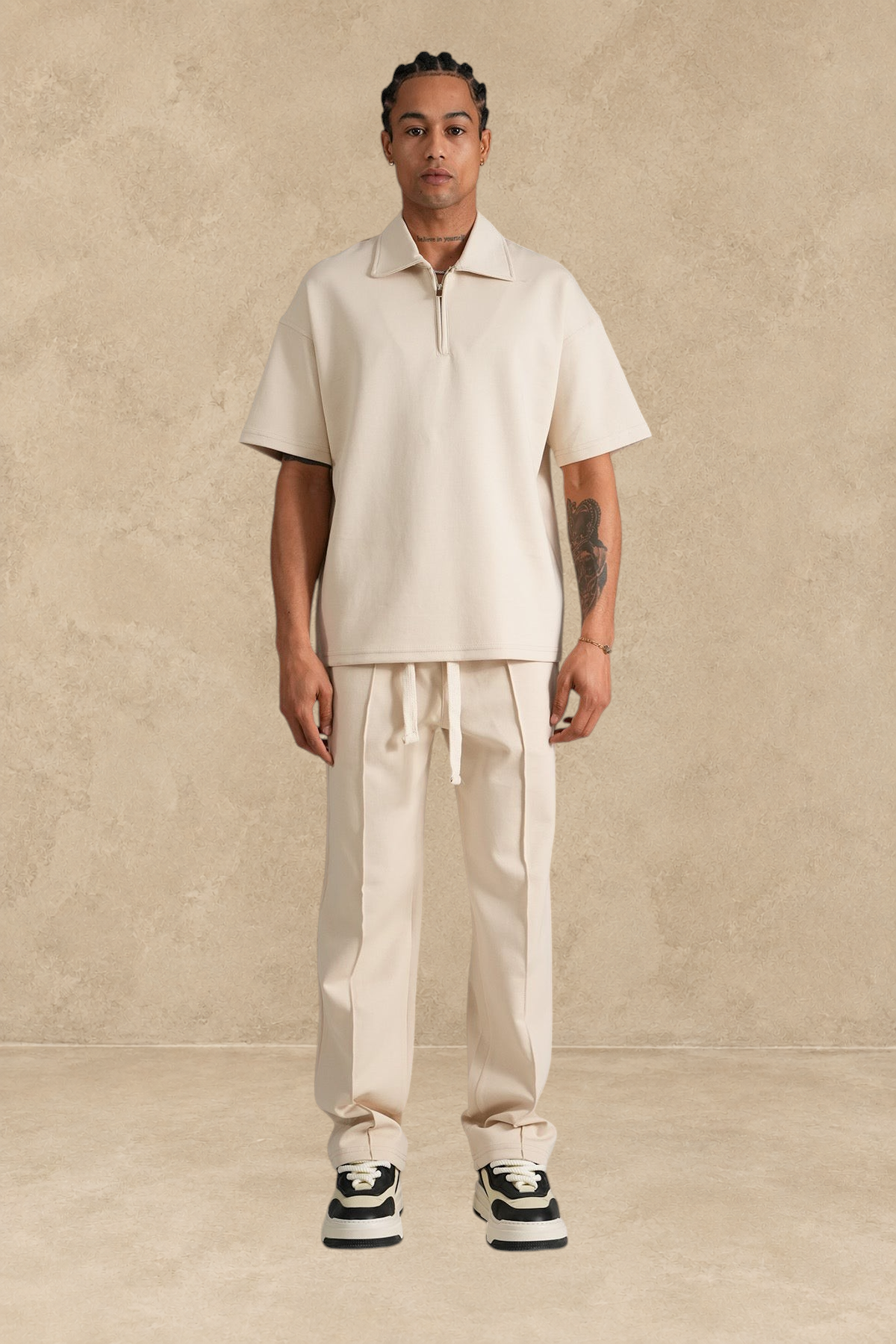 Ensemble Stayin beige composé d'un polo à zip et d'un pantalon coupe large en polyester porté par un mannequin