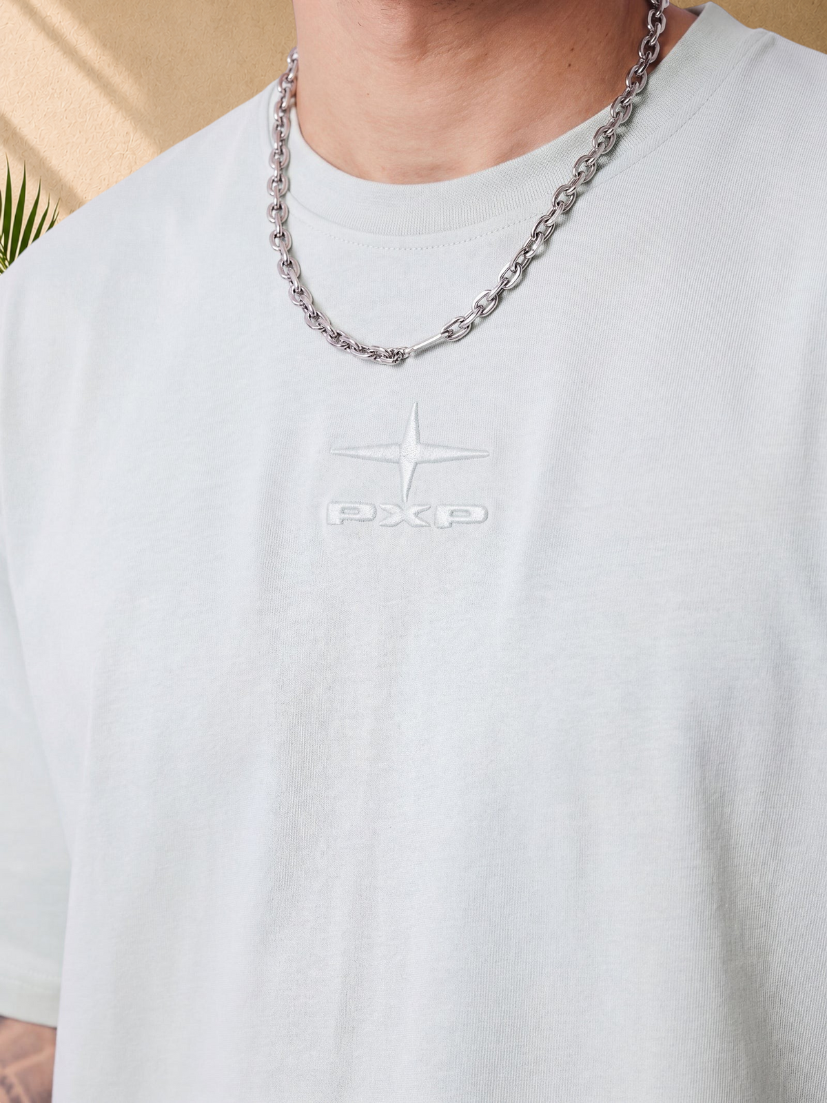 Stayin mint green boxy cotton t-shirt with tonal embossed PXP logo on chest, worn with a silver chain necklace