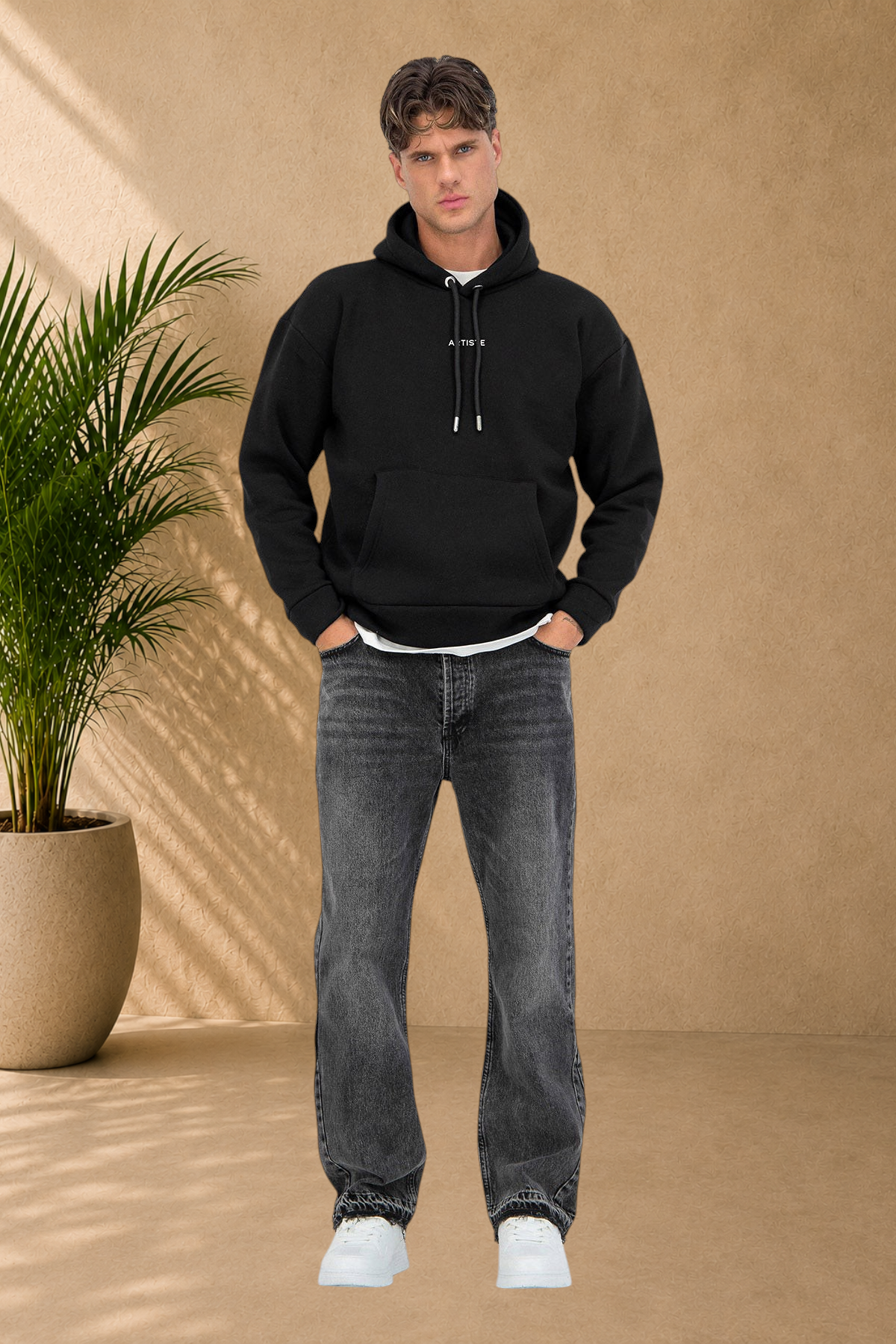 Stayin black quilted hoodie with a front pocket worn by a male model with grey jeans and white sneakers