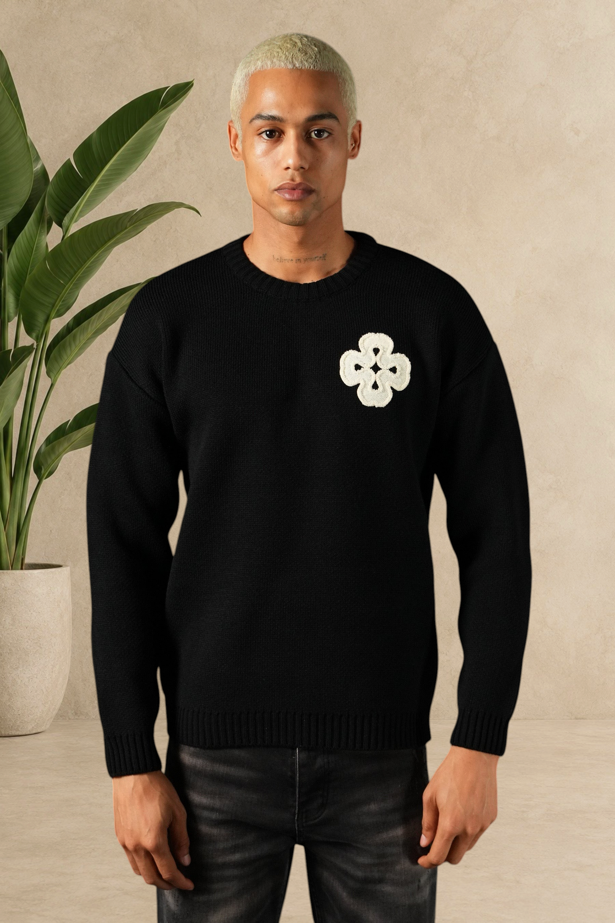 Mannequin portant un pull Stayin noir en maille épaisse avec un motif trèfle blanc brodé sur la poitrine
