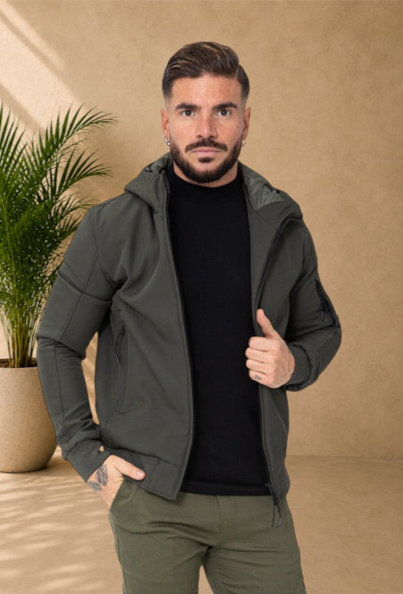 Stayin khaki hooded windbreaker jacket worn by a man with a black turtleneck against a white background