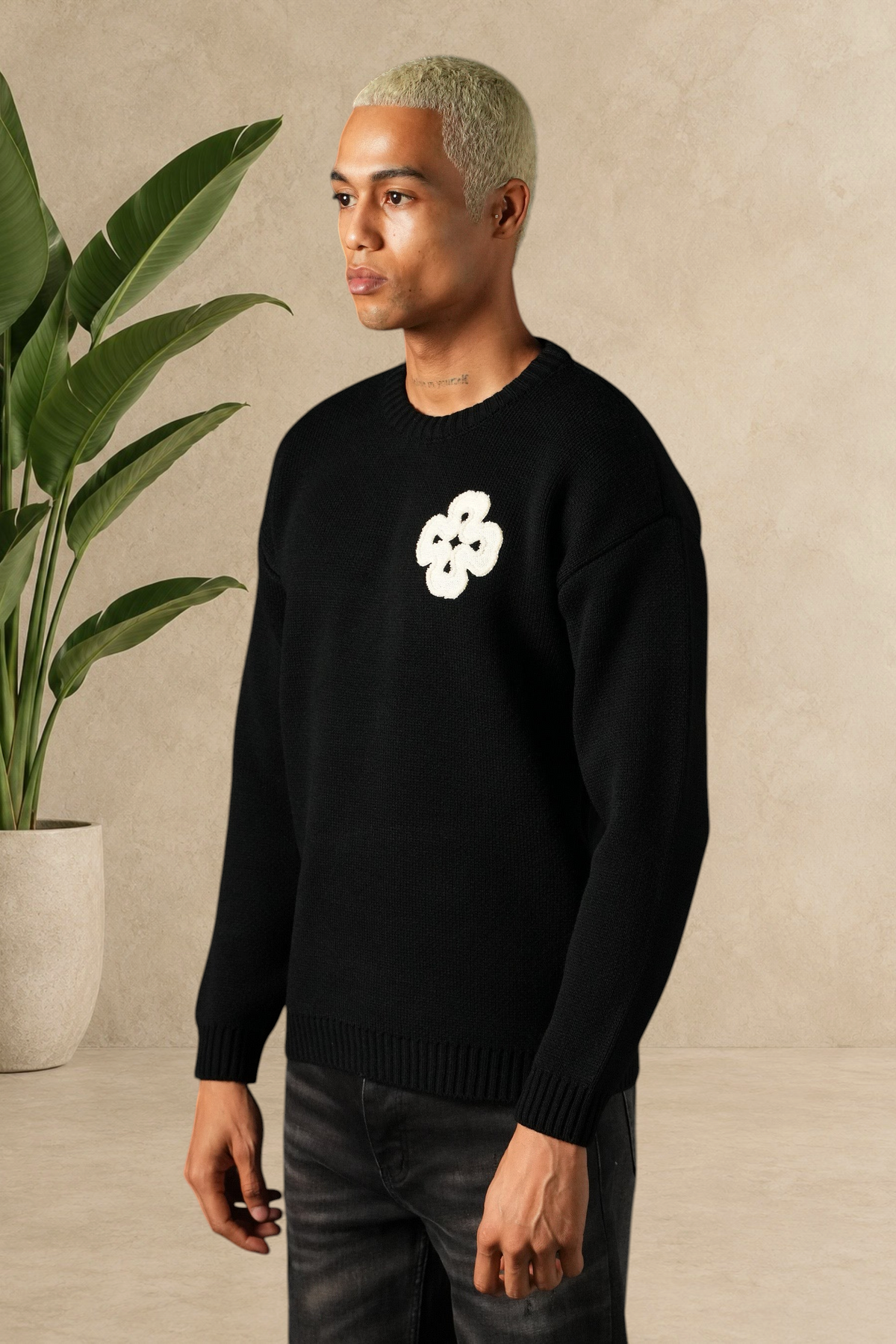Mannequin portant un pull Stayin noir en maille épaisse avec un motif trèfle blanc sur la poitrine