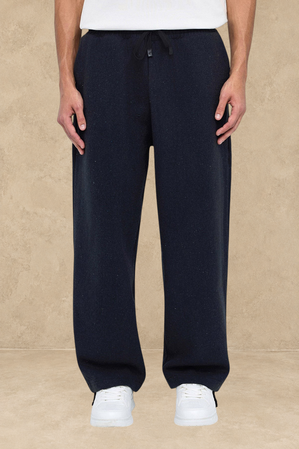 Pantalon Oxford noir Stayin à coupe large avec cordon de serrage, porté par un mannequin avec des baskets blanches