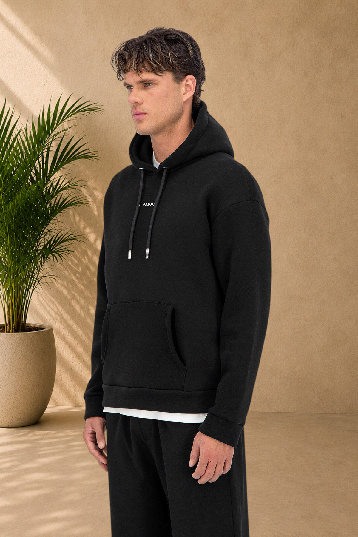 Stayin black Amore quilted hoodie worn by a male model, featuring a drawstring hood and front pocket.
