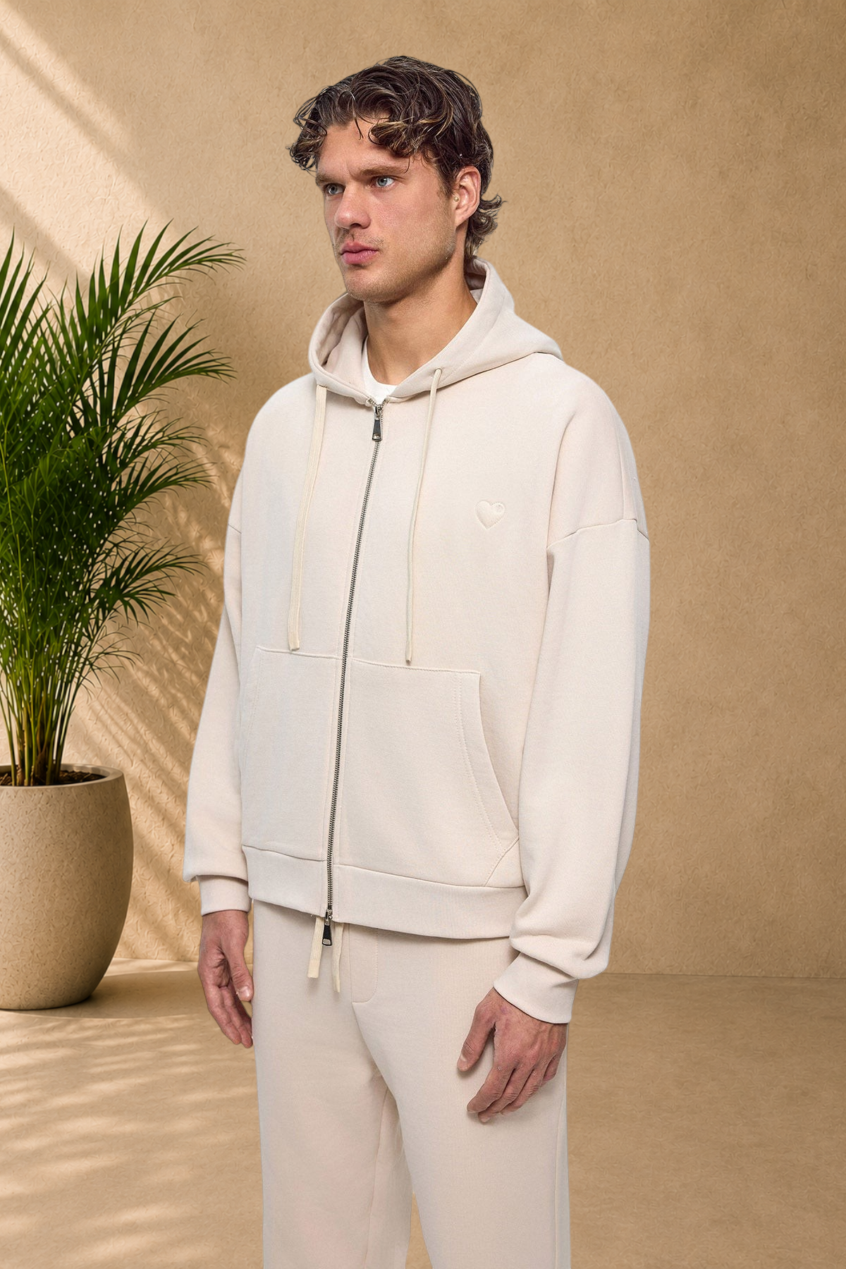 Stayin beige quilted zip-up hoodie with a small heart detail worn by a male model