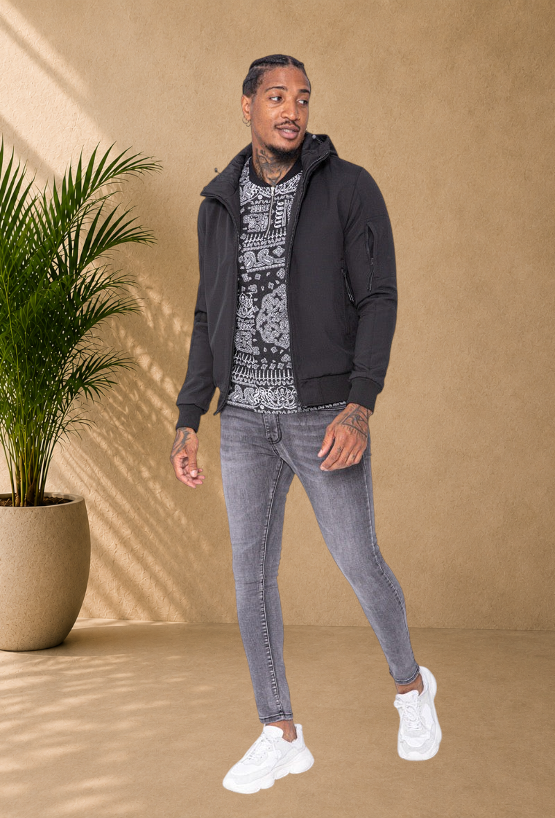 Stayin black hooded windbreaker jacket worn by a model with grey skinny jeans and white sneakers
