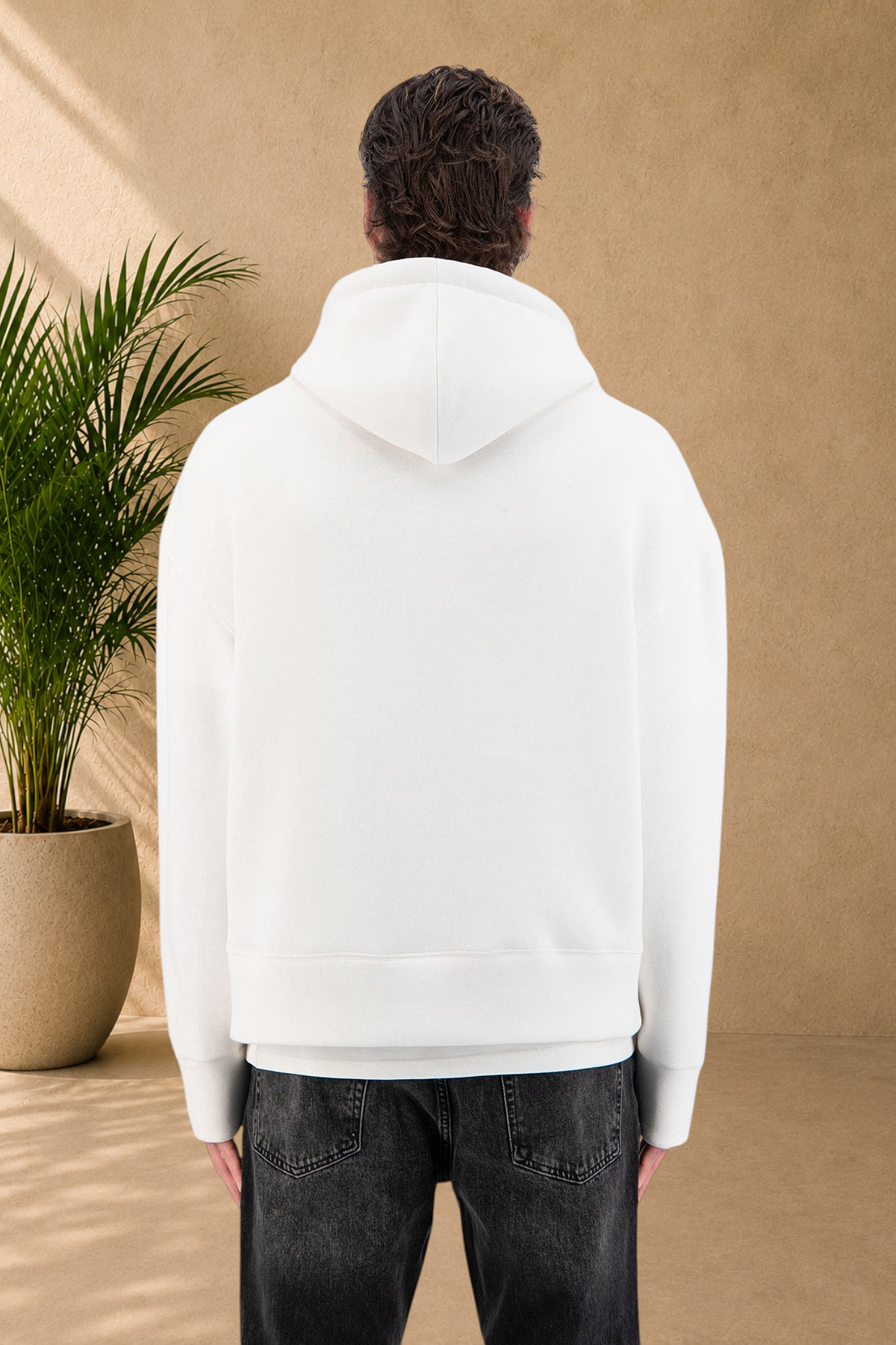 Back view of a man wearing a Stayin white thick quilted hoodie with a small heart detail, paired with black jeans.