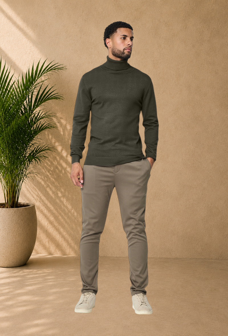 Stayin model wearing a slim-fit khaki turtleneck sweater with beige trousers and sneakers in a studio setting.