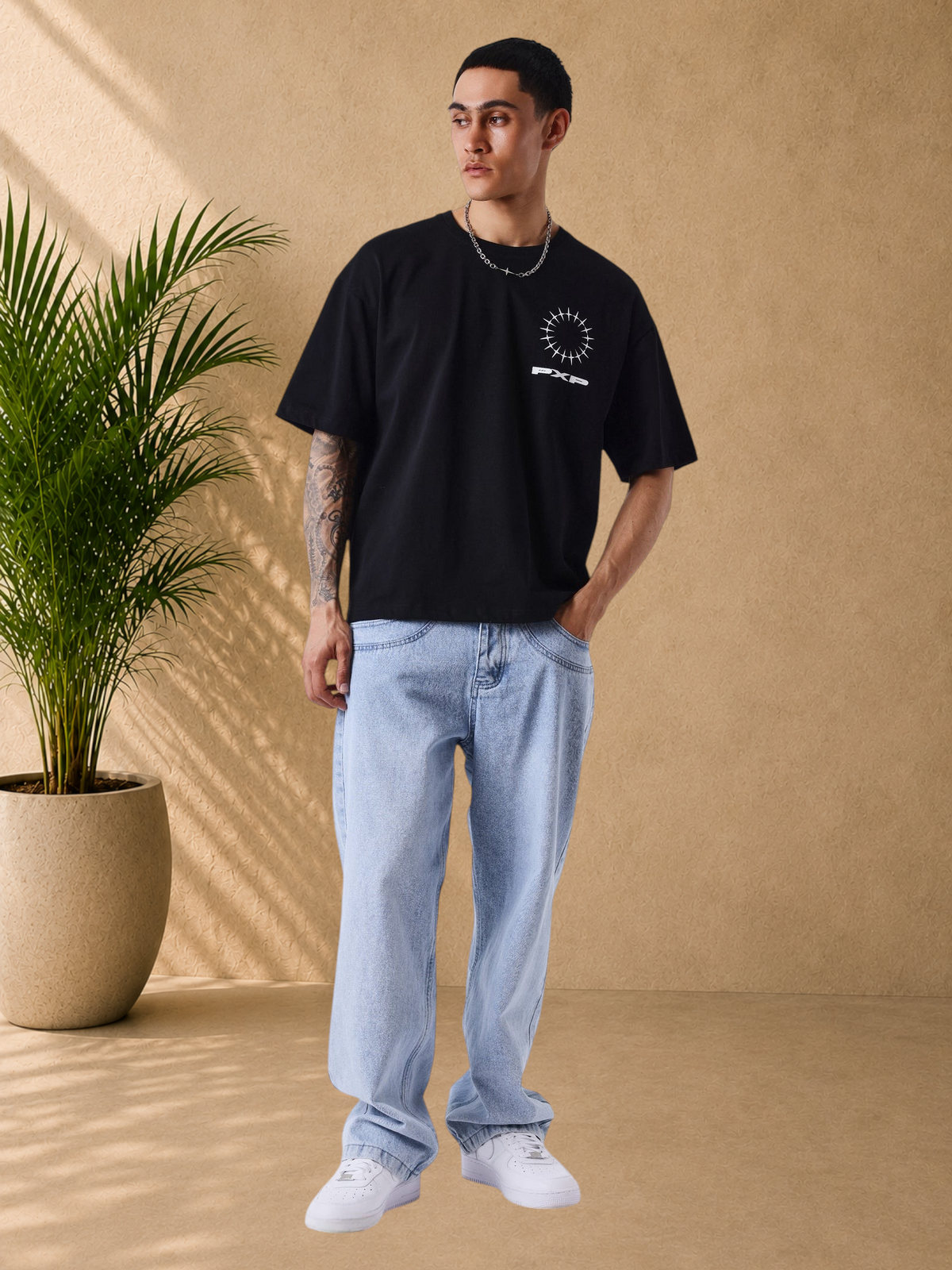 Stayin oversized black cotton t-shirt with white graphic logo on chest and back, worn by a male model