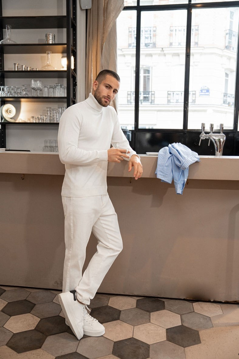 Stayin white slim-fit turtleneck sweater worn by a man in a modern cafe setting