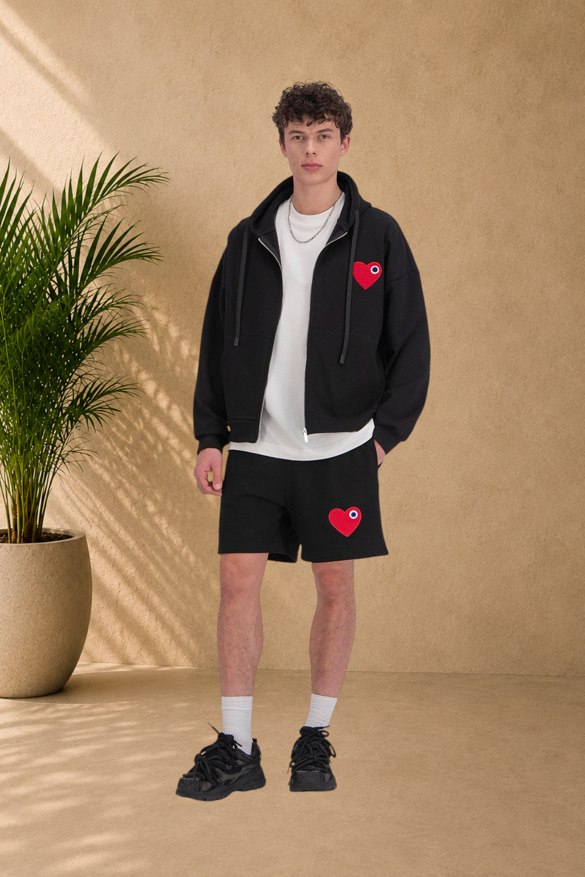 Stayin black quilted zip-up hoodie with red heart embroidery worn by a male model with matching black shorts