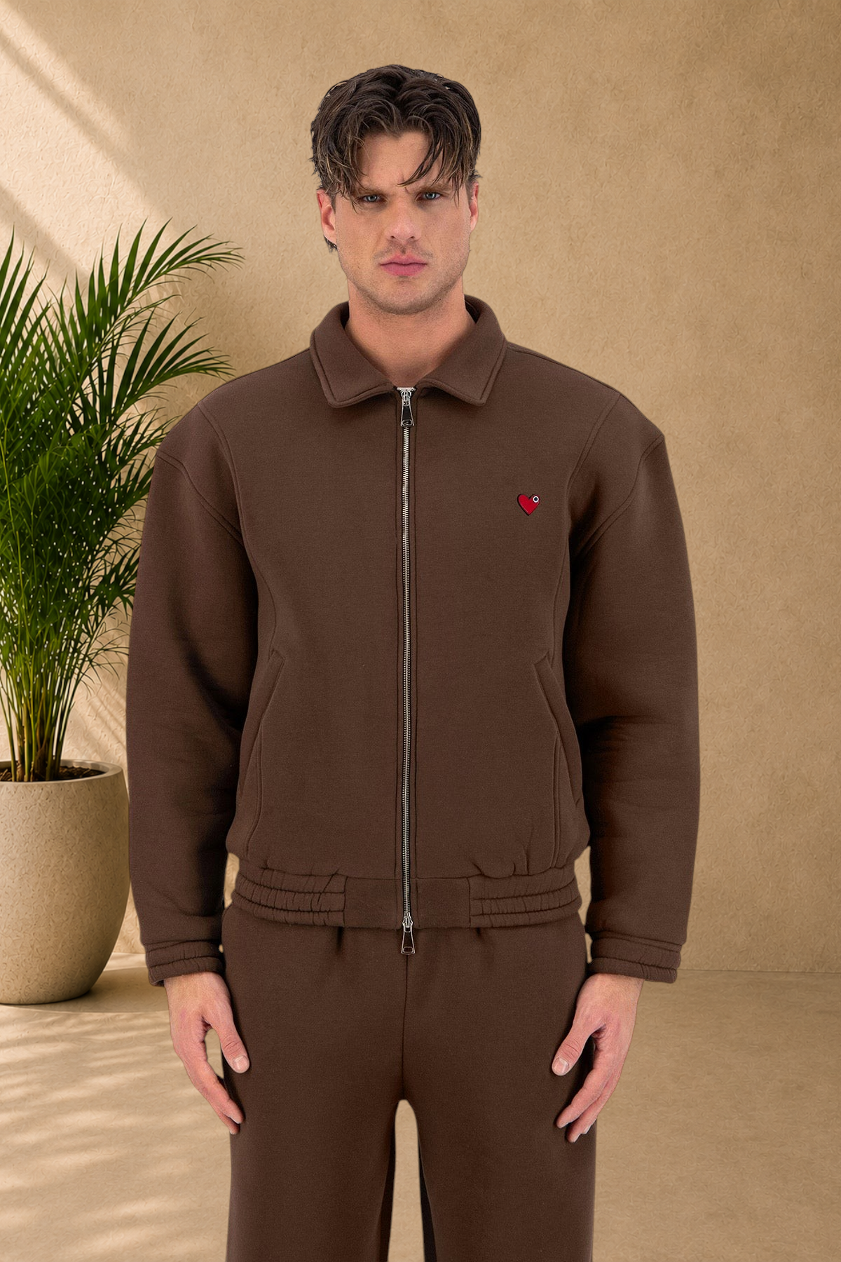 Stayin brown oversized padded zip-up jacket with a small red heart detail worn by a male model