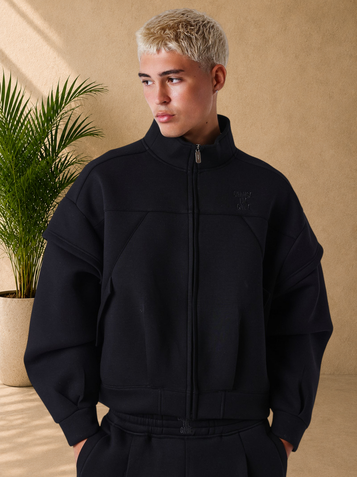 Stayin black neoprene boxy zip-up jacket with high collar, structured panels, and ribbed cuffs on a male model.