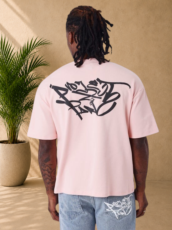 Stayin oversized pink cotton t-shirt with black graffiti graphic print on the back worn by a man