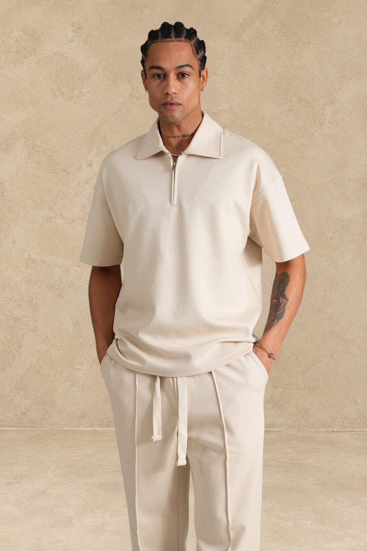 Ensemble Stayin beige composé d'un polo à zip et d'un pantalon coupe large en polyester porté par un mannequin