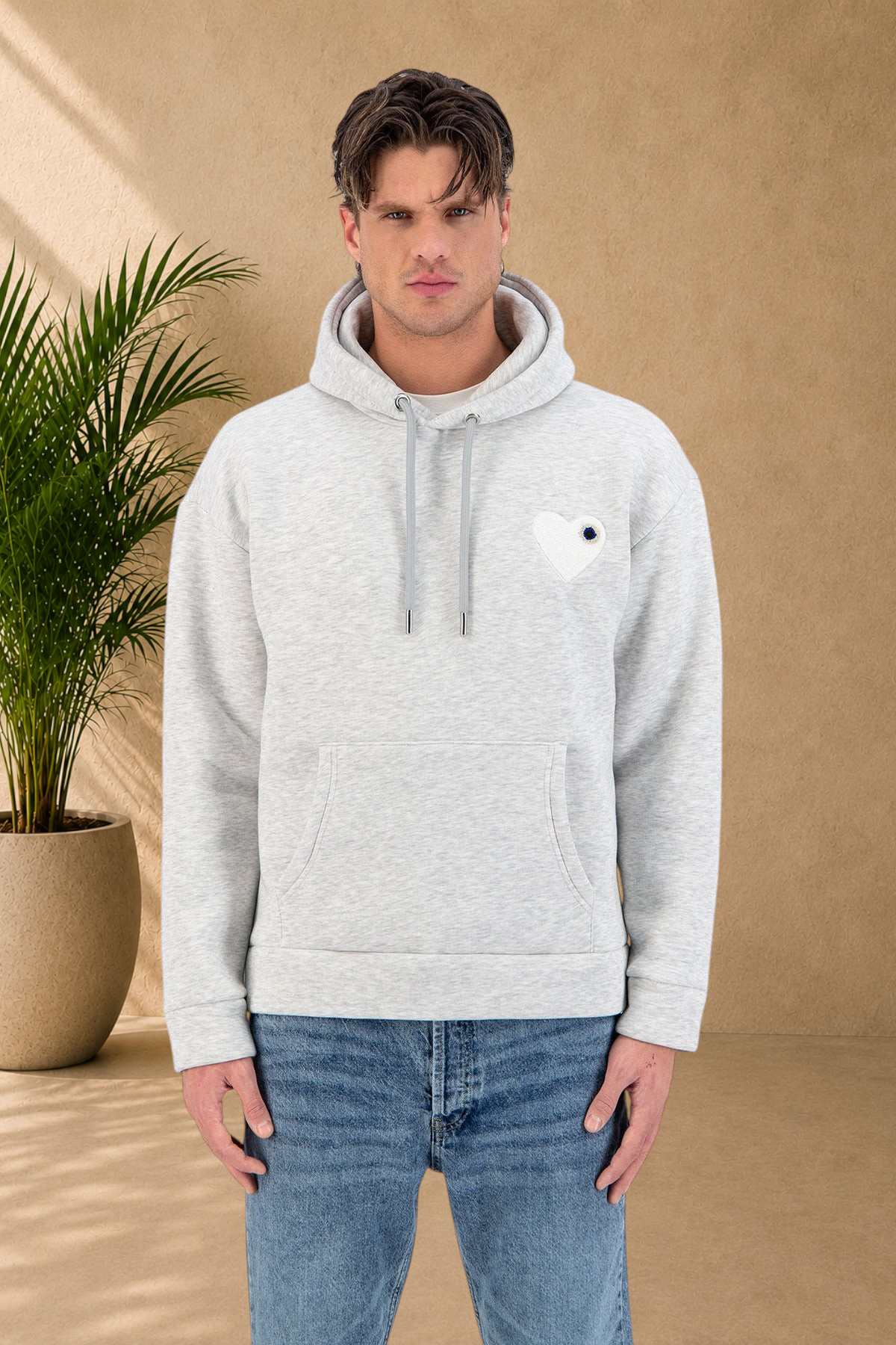 Stayin grey quilted hoodie with a black heart patch worn by a male model in a studio setting