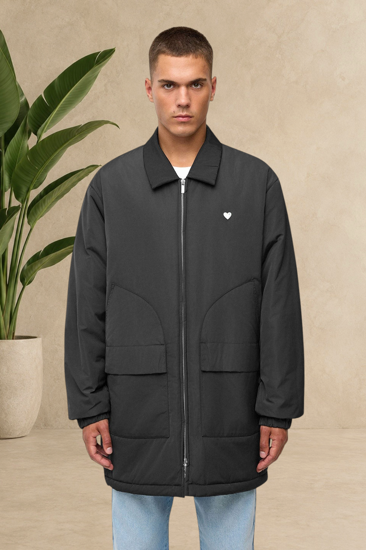 Homme portant une parka doudoune longue noire Stayin avec col chemise, poches frontales et logo cœur blanc