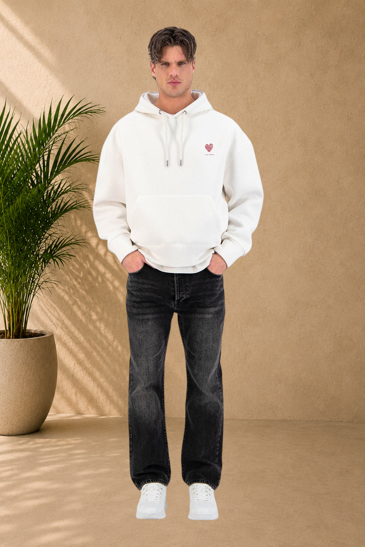 Stayin white hoodie with red heart embroidery worn by a male model in black jeans against a white background