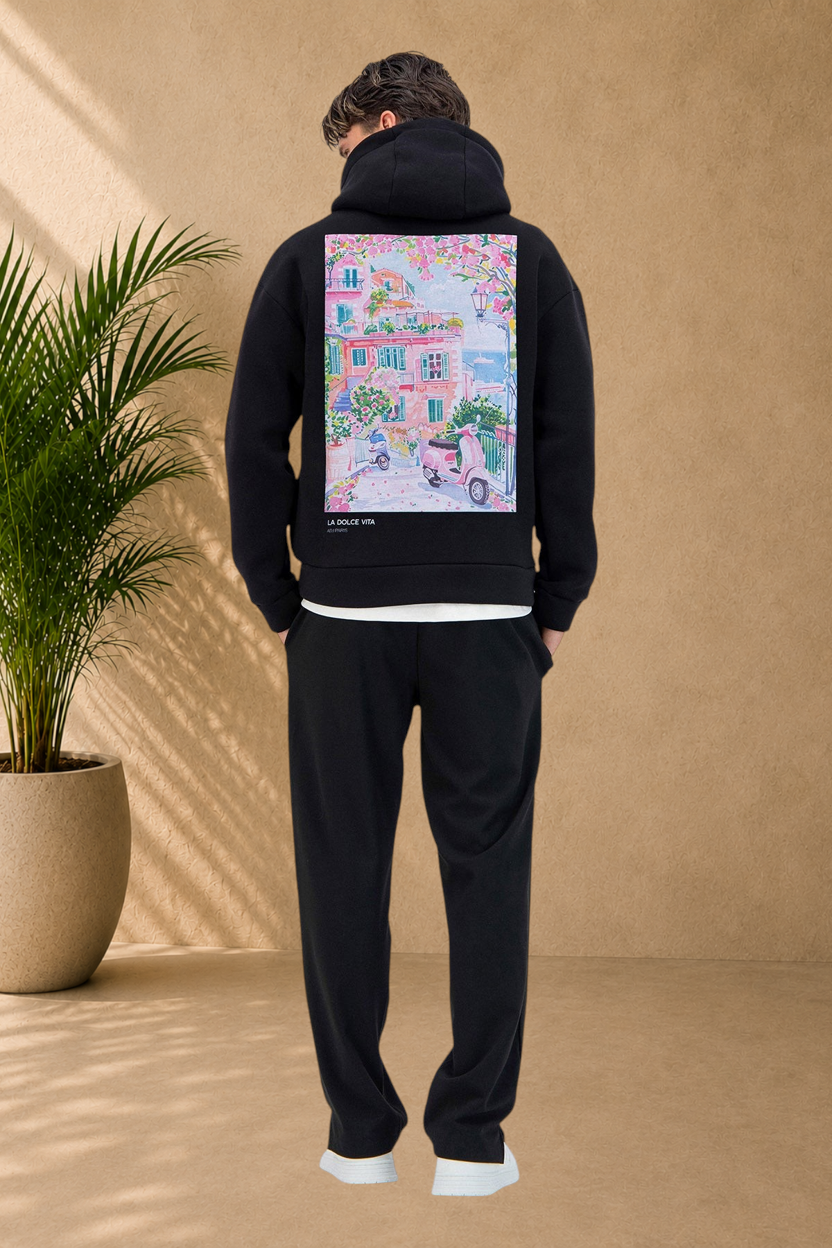 Stayin black quilted hoodie with Dolce Vita graphic print on back worn by a man standing in a studio setting