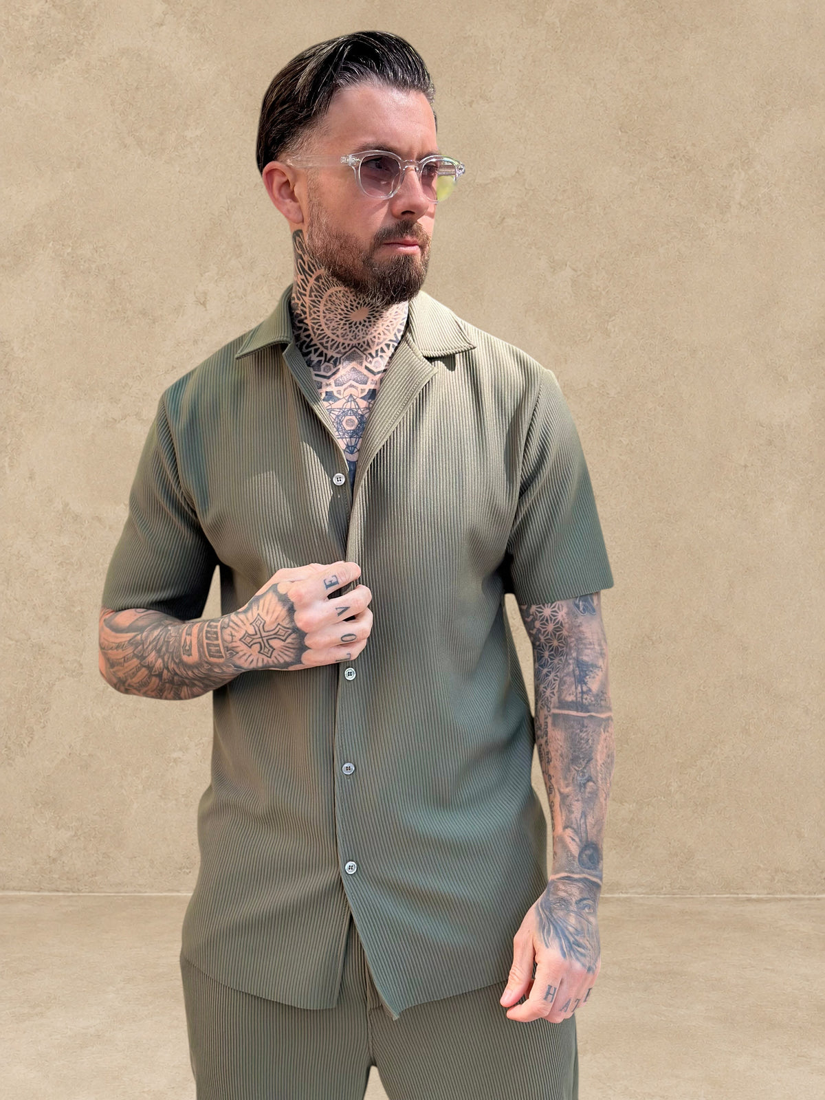 Homme tatoué portant un ensemble Stayin chemise à manches courtes et pantalon droit texturé de couleur kaki