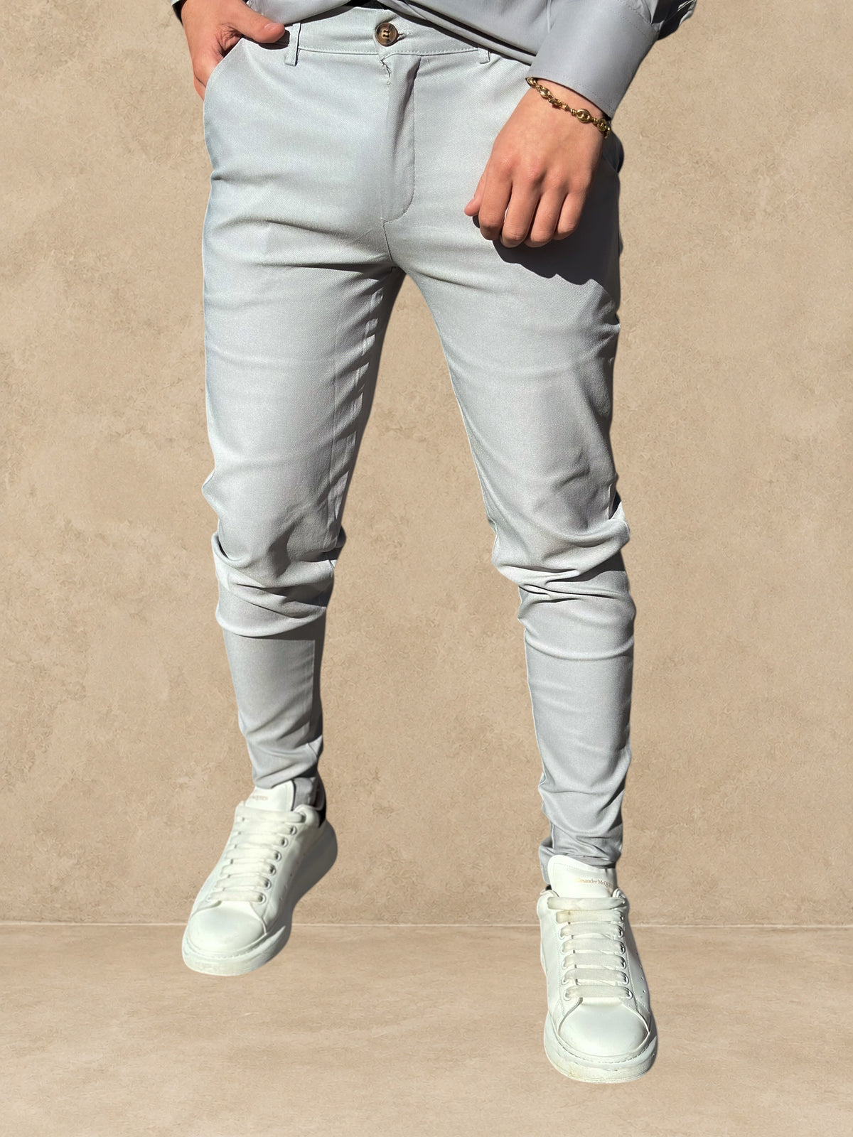 Pantalon Stayin gris à coupe cintrée et style pince porté par un homme avec des baskets blanches